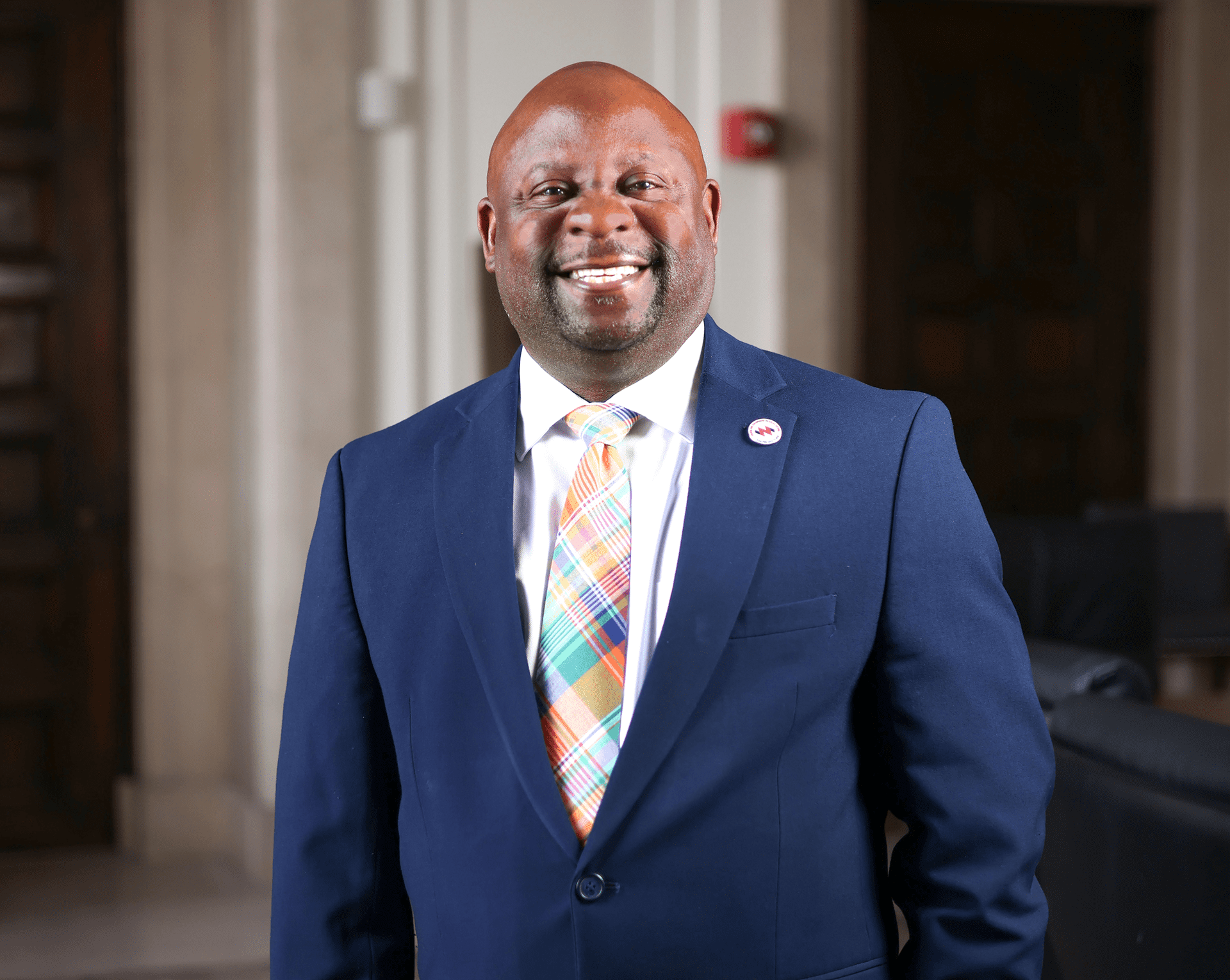 Man in suit smiling indoors.